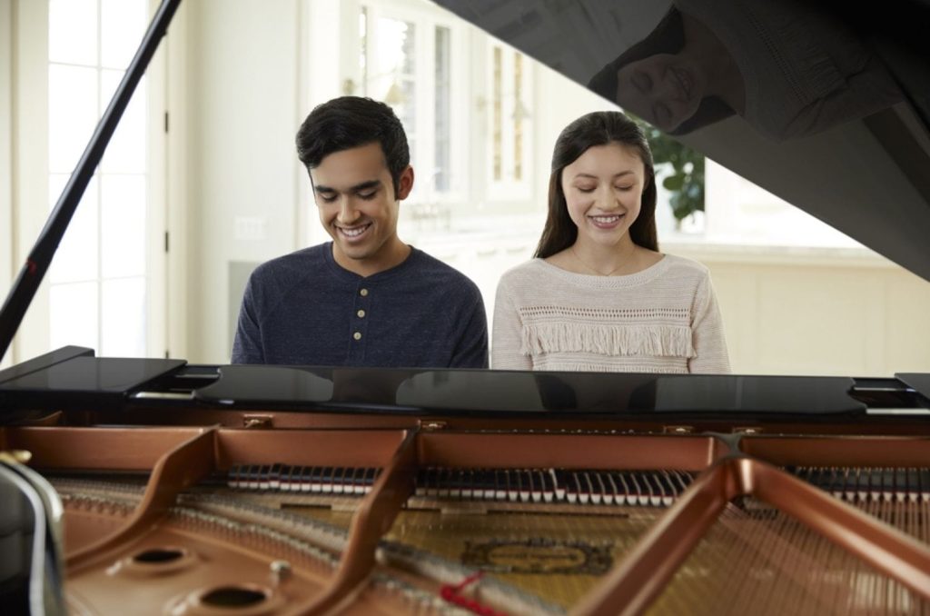 Couple playing a Yamaha Grand piano